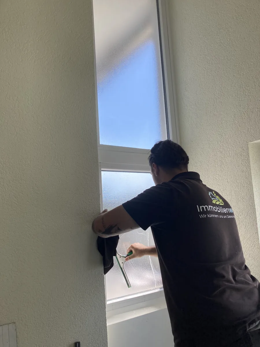 Mitarbeiter von Immobilienwart zieht ein Fenster mit dem Gummiabzieher ab