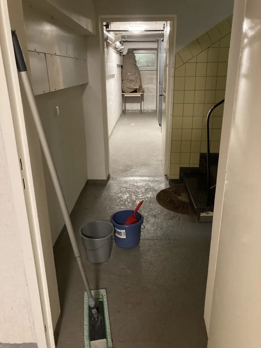 Frisch feucht gewischter Kellerflur mit Wischmopp und Eimern